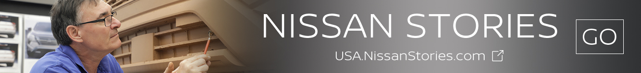 A man holding a tool while working on a scale model of a vehicle.