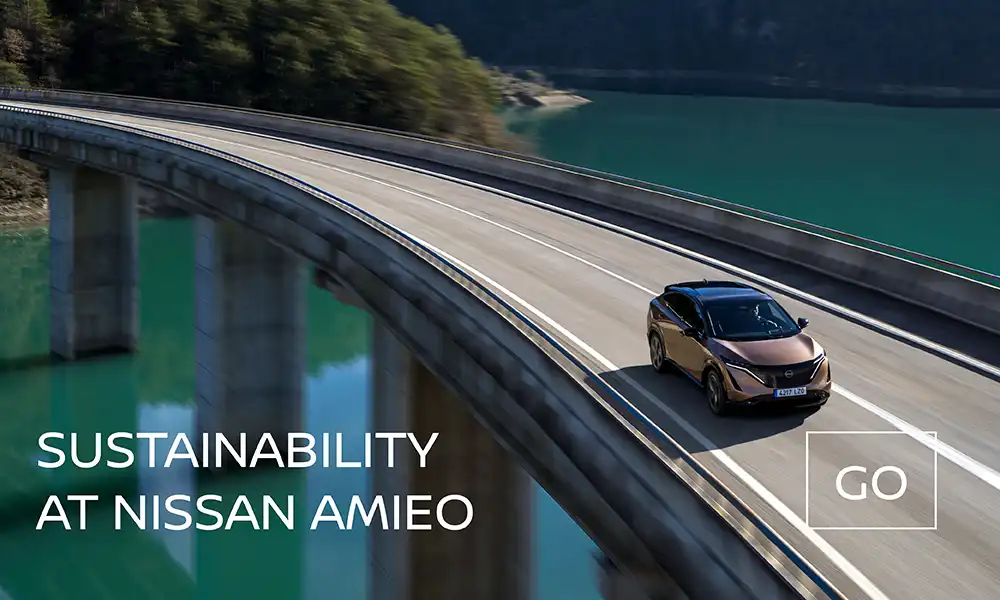 Front view of Nissan Ariya driving on a bridge with the text that says Sustainability at Nissan AMIEO
