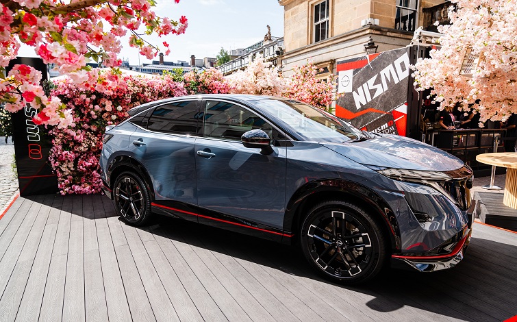 Side view static shot of the Ariya Nismo at Covent Garden with artificial cherry blossom and Nismo branding in the background.