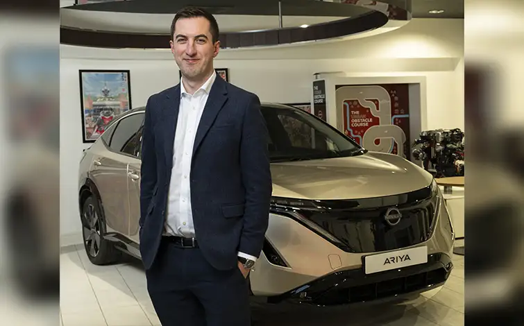 Matt Duncan standing in front of a silver Nissan Ariya electric vehicle.
