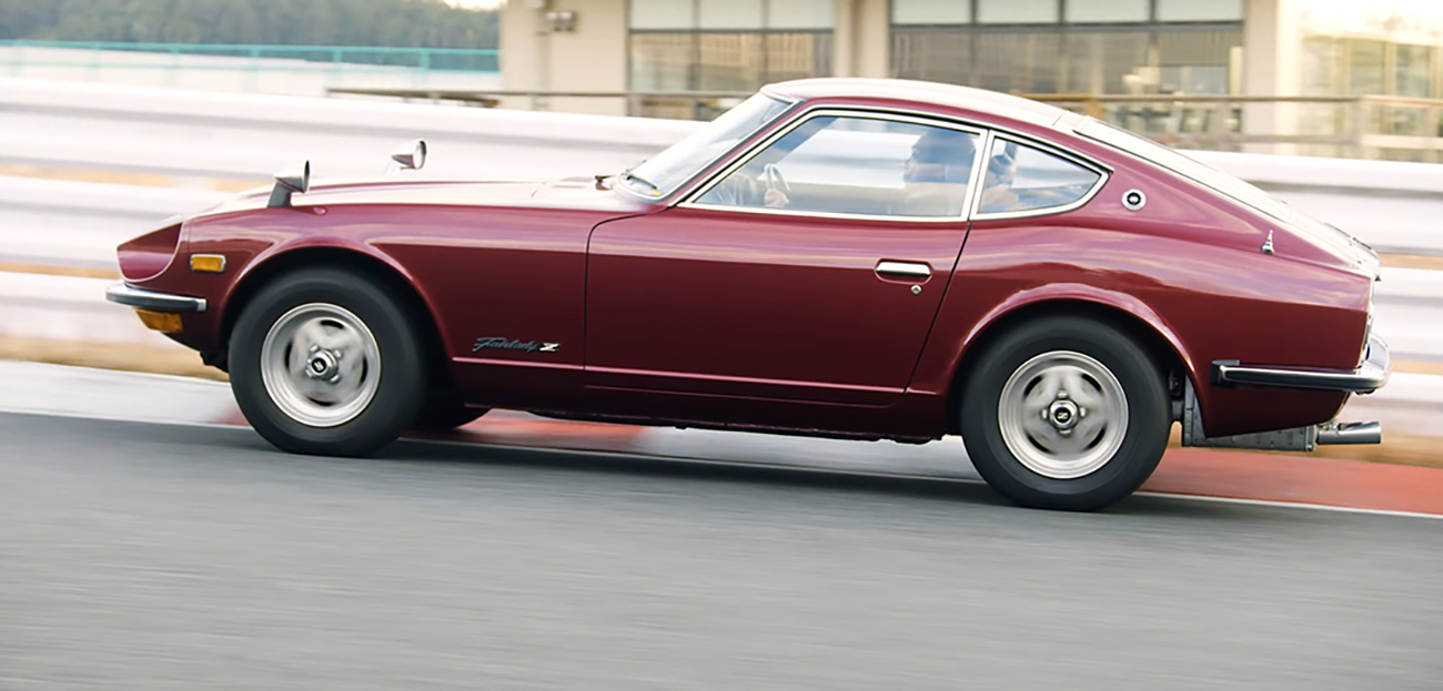 A red Nissan Z driving uphill in a city.
