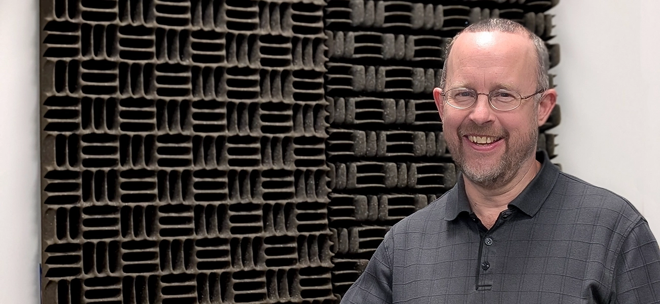 Patrick standing and smiling in front of a cushioned sound-proofed wall.