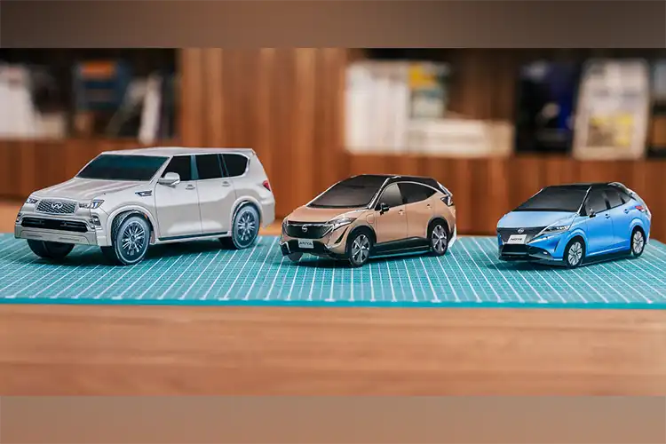3 coches de papel Nissan sobre una mesa.