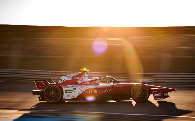 早朝、金色の朝日が差し込み、コースを走行するノーマン ナトーのフォーミュラEマシンに長い影が落ちている。