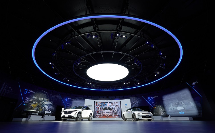 Inside the guest hall. Nissan cars are on display under a circular, outer space-like ceiling.
