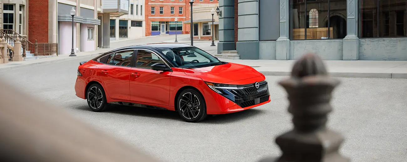 Front right 3/4 view of the 2026 Nissan Sentra driving on a city pathway.