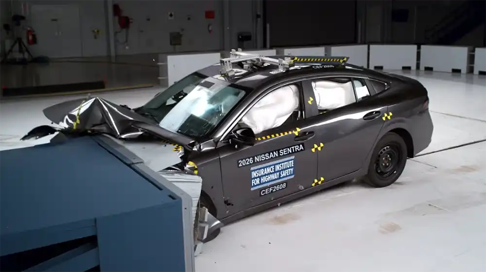 2026 Nissan Sentra crash car after a frontal impact with a barrier, showing deployed airbags and front‑end damage.