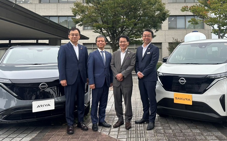 電気自動車の前で記念撮影をする、京田辺市、同支社大学、日産自動車の各団体代表者