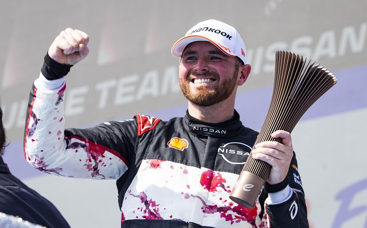 サンパウロ大会で3位表彰台獲得した日産フォーミュラEチームのオリバ ーローランド。左手にトロフィー、右手でガッツポーズ。