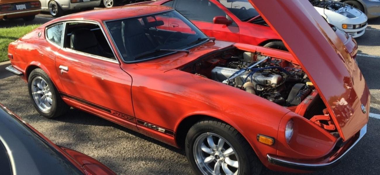A classic red Nissan Z with its hood open.