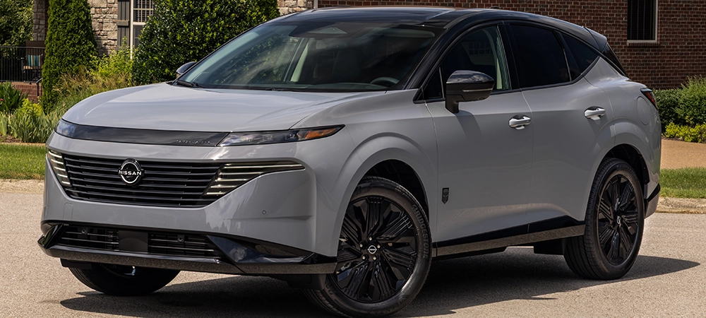 Front left 3/4 view of the 2027 Nissan Murano Dark Armor parked in front of a residential house.