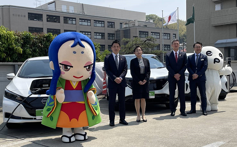 電気自動車の前で記念撮影する各代表者