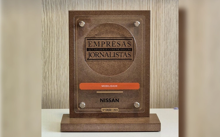 Troféu do prêmio com os dizeres gravados em destaque ‘’Empresas que melhor se comunicam com jornalistas’’, abaixo em destaque laranja escrito ‘’Mobilidade’’, o logo da Nissan e os dizeres gravados em fonte pequena ‘’Décima quarta edição dois mil e vinte e quatro’’