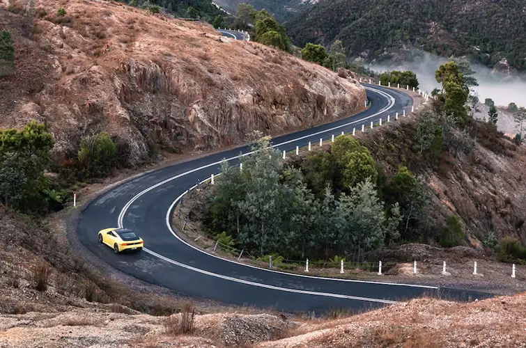 A yellow Nissan Z driving on a curved mountain road