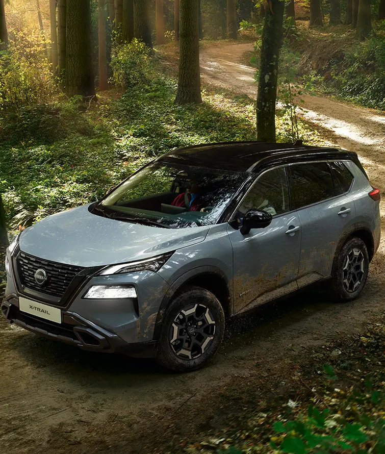 Nissan X-Trail in hellblau fährt über einen unbefestigten Waldweg