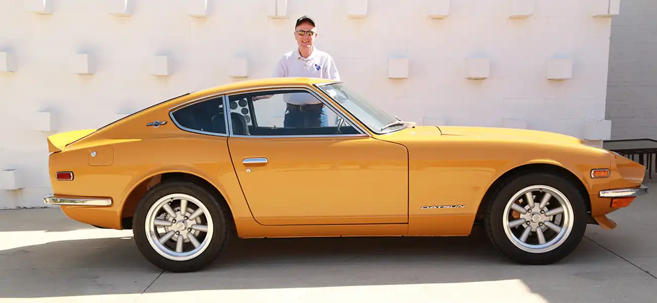 A yellow Z with a man standing behind it.