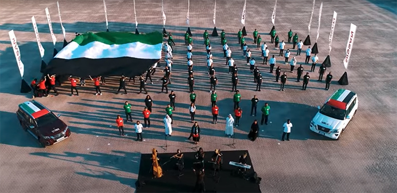 Nissan UAE employees lining up in the parking lot with the flag of UAE.
