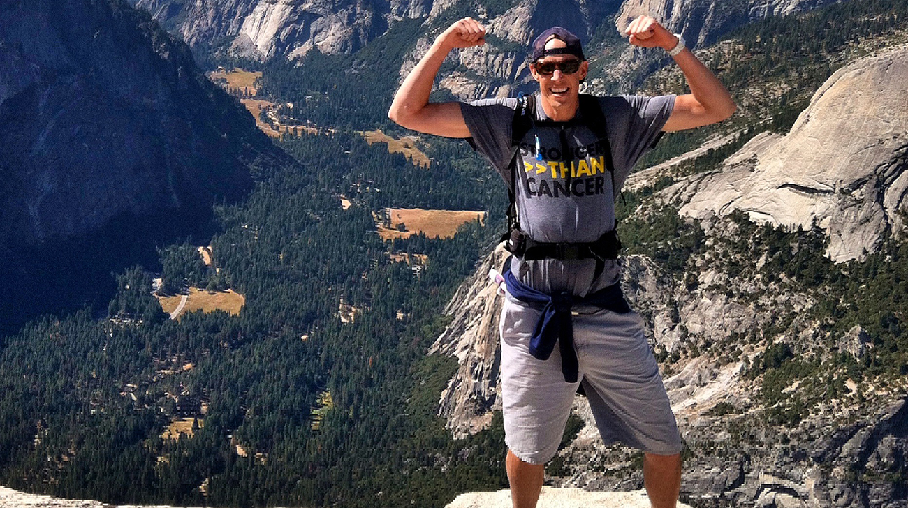 A man pausing at the top of a mountain.