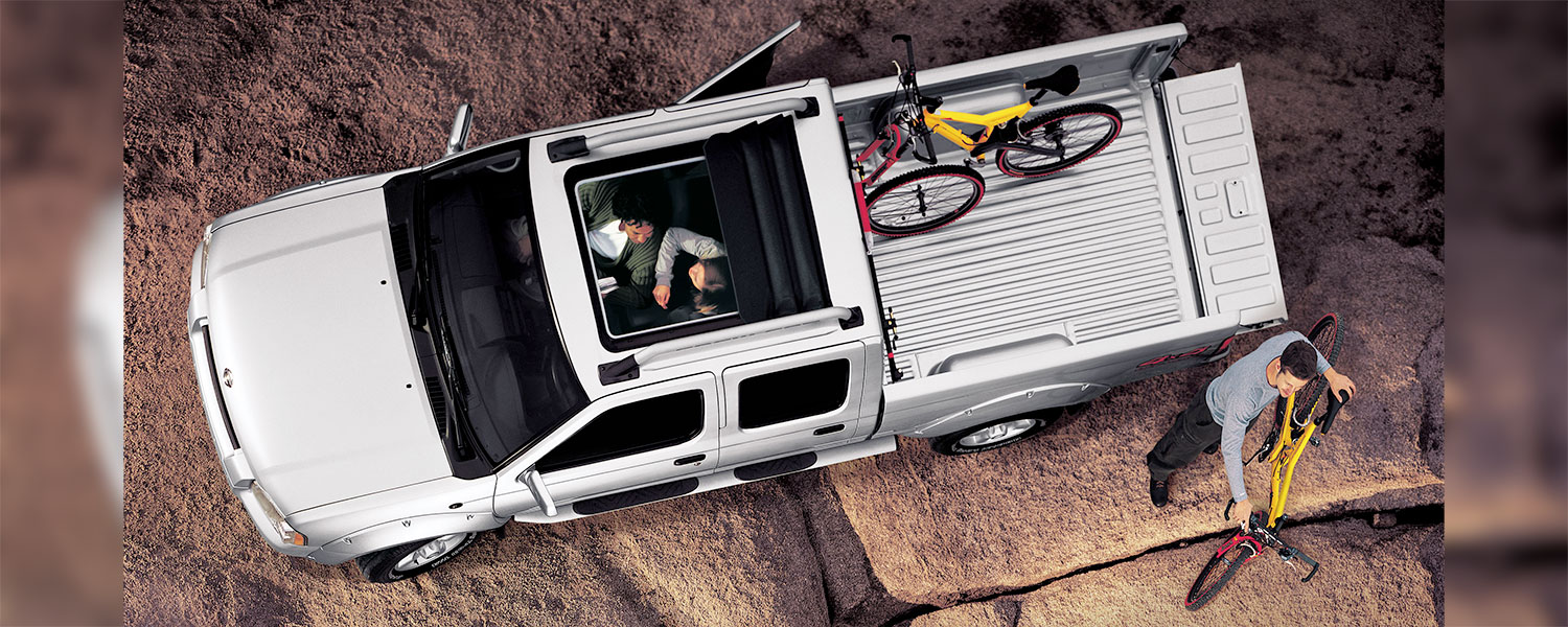 An aerial view of a Nissan Frontier with a person unloading bicycles from the cargo bed