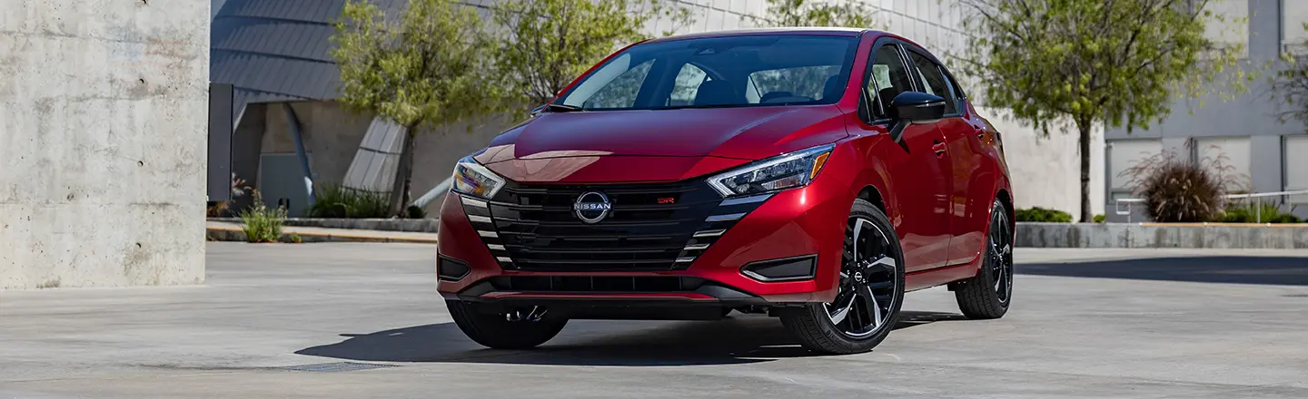 A red 2023 Nissan Versa parked in a parking lot.