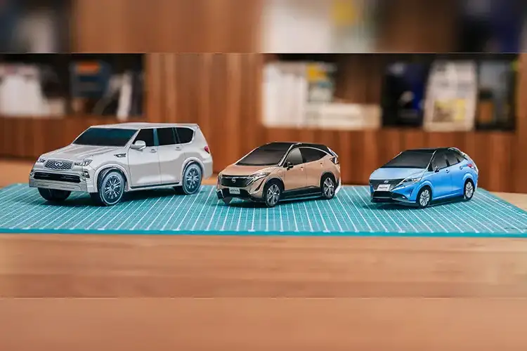 A photo of 3 paper Nissan cars on a table mat.