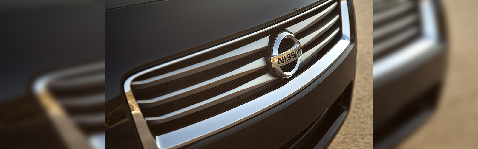 A close up picture of the emblem for a black Nissan Maxima.