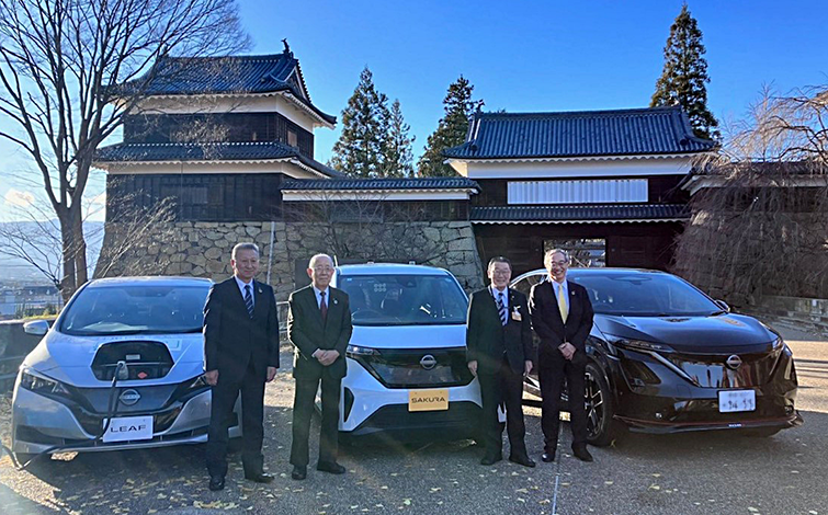 電気自動車の前で記念撮影する各代表者