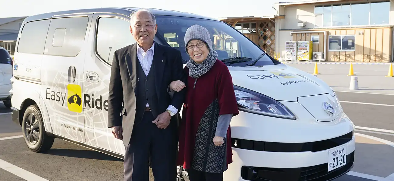 Two people smiling and standing in front of white van