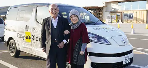 Two people smiling and standing in front of white van