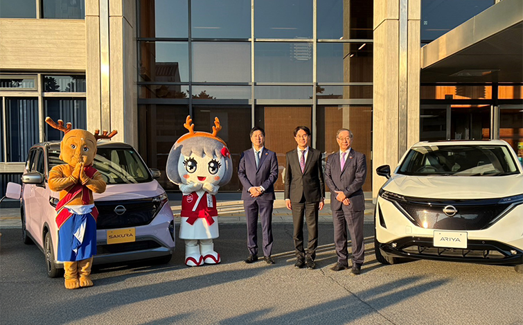 電気自動車の前で記念撮影をする各団体代表者