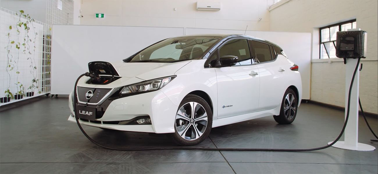 A white Nissan Leaf parked at a charging station