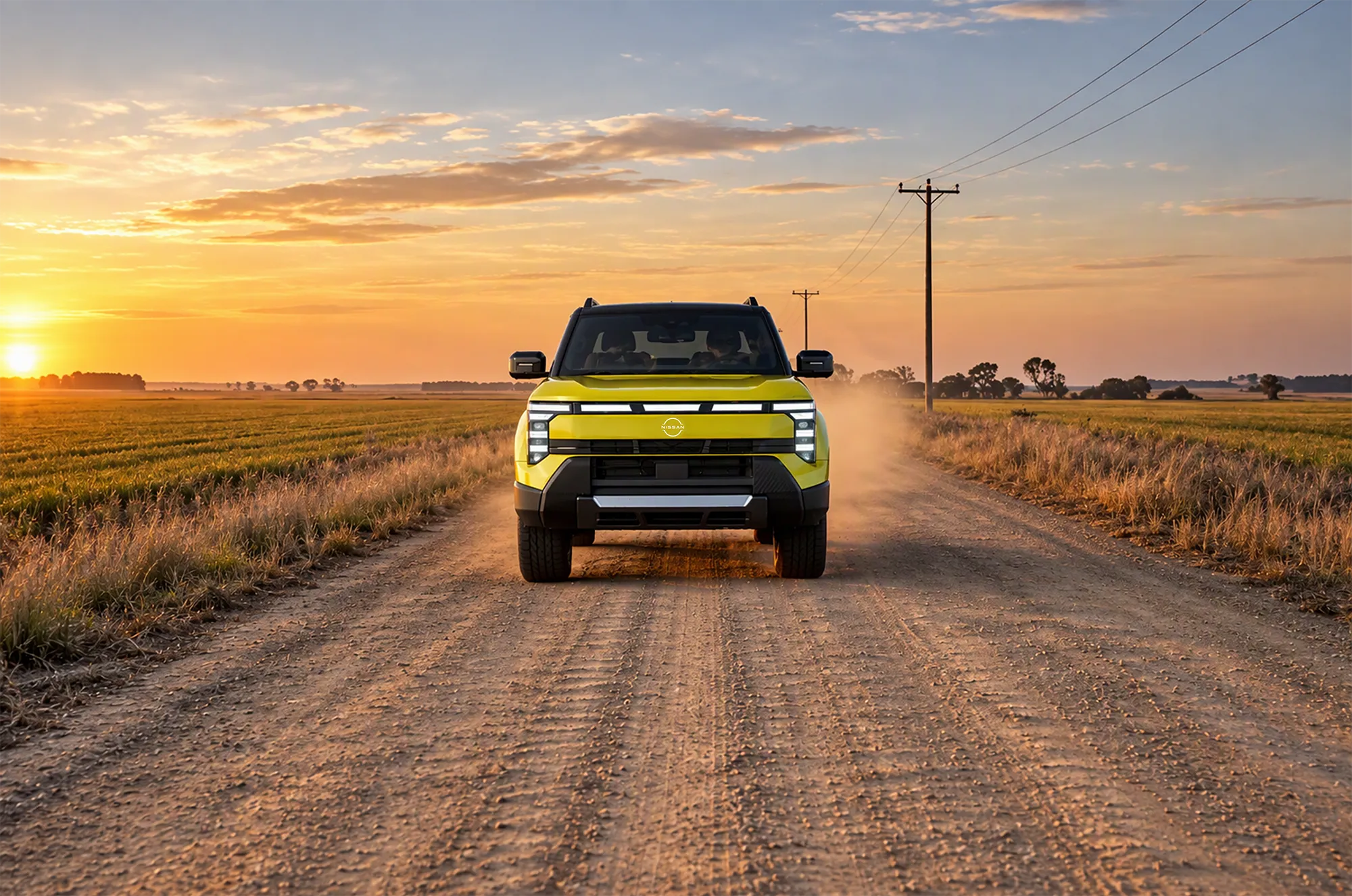 Front view of a 2027 Nissan Navara Pro PHEV driving along a rural Australian dirt road at sunset.