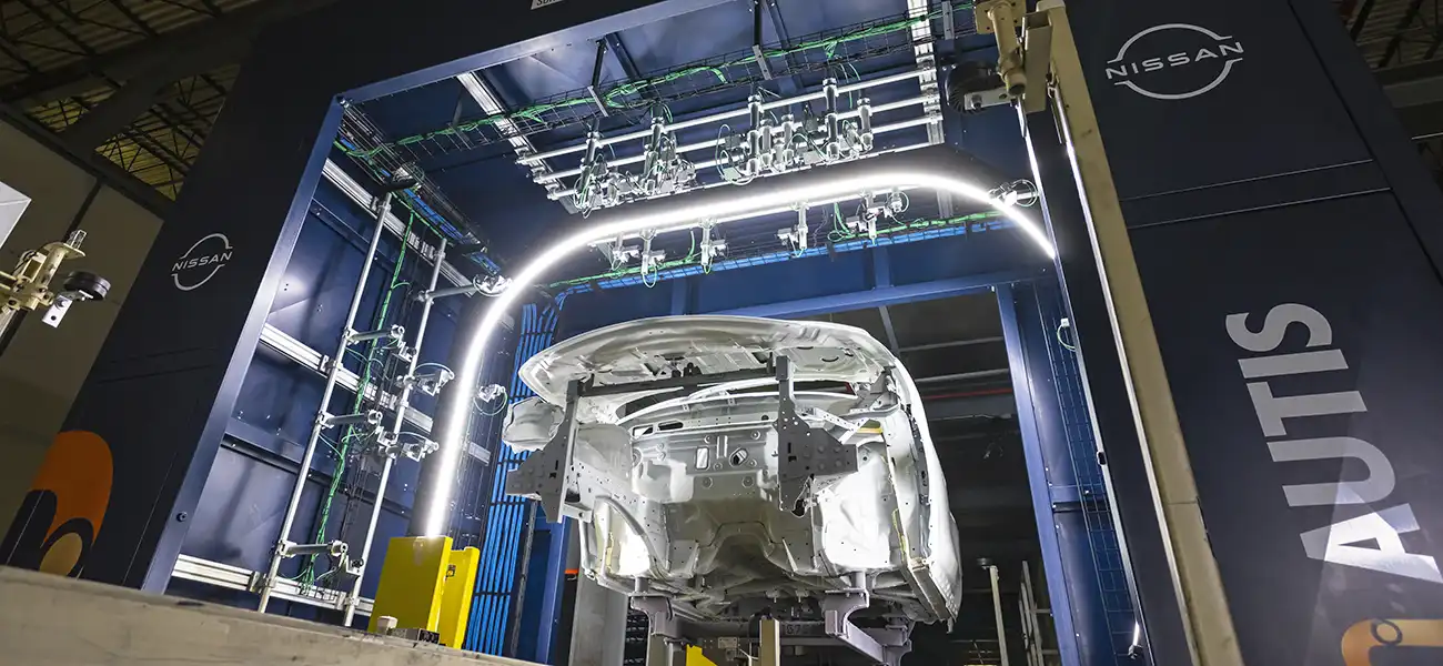 Imagem de uma carroceria branca na fábrica da Nissan com luzes ao redor para inspeção da qualidade da pintura.