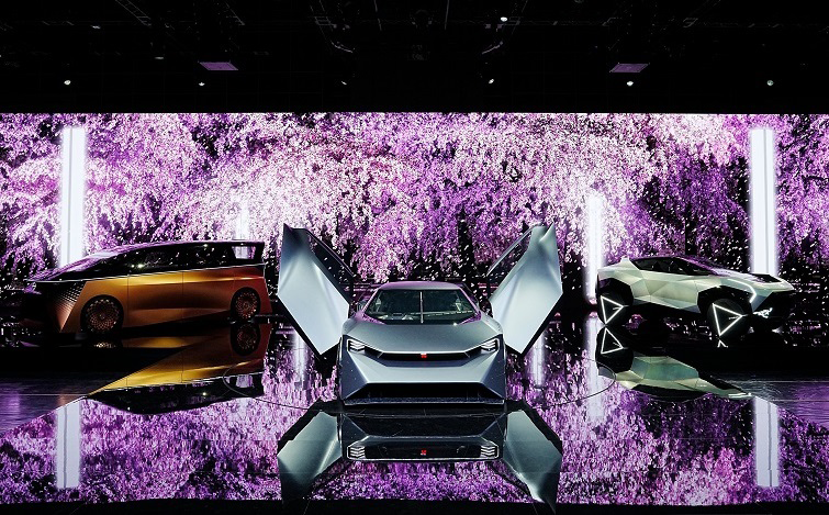 TOKYO MOBILITY SHOW 2023 日産ブースのステージで披露されている日産のコンセプトカー3台。床・壁面に美しい桜の映像が投影されている。