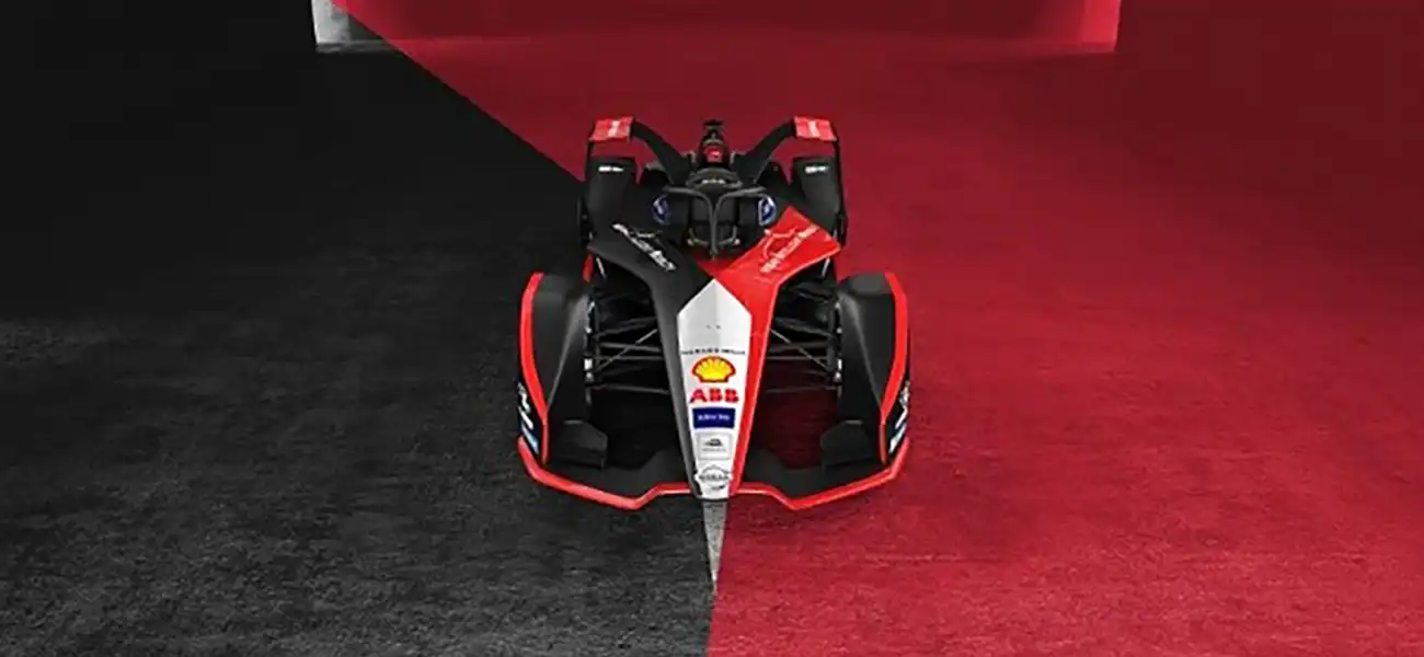 A formula E race car parked in a red and black space.