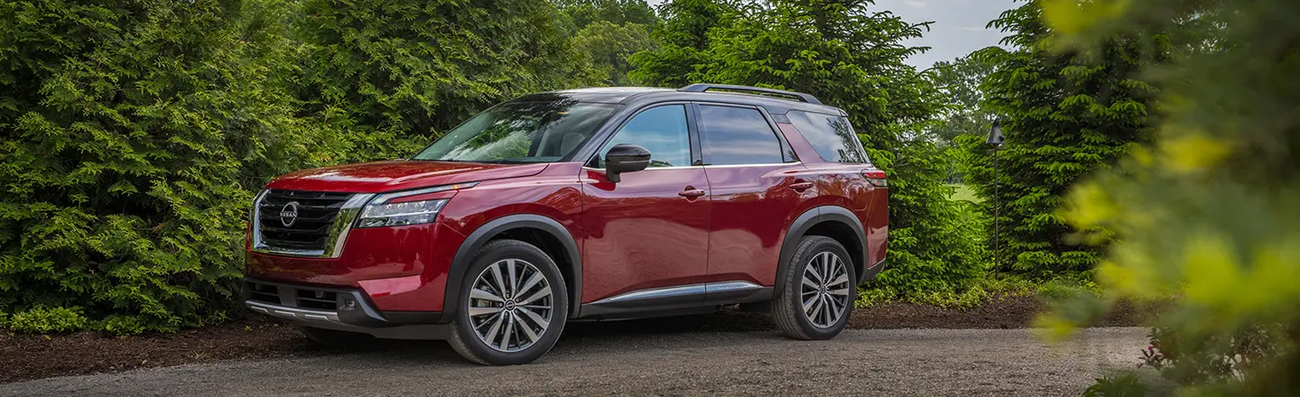 Le Nissan Pathfinder 2024 un chemin de terre dans les bois.
