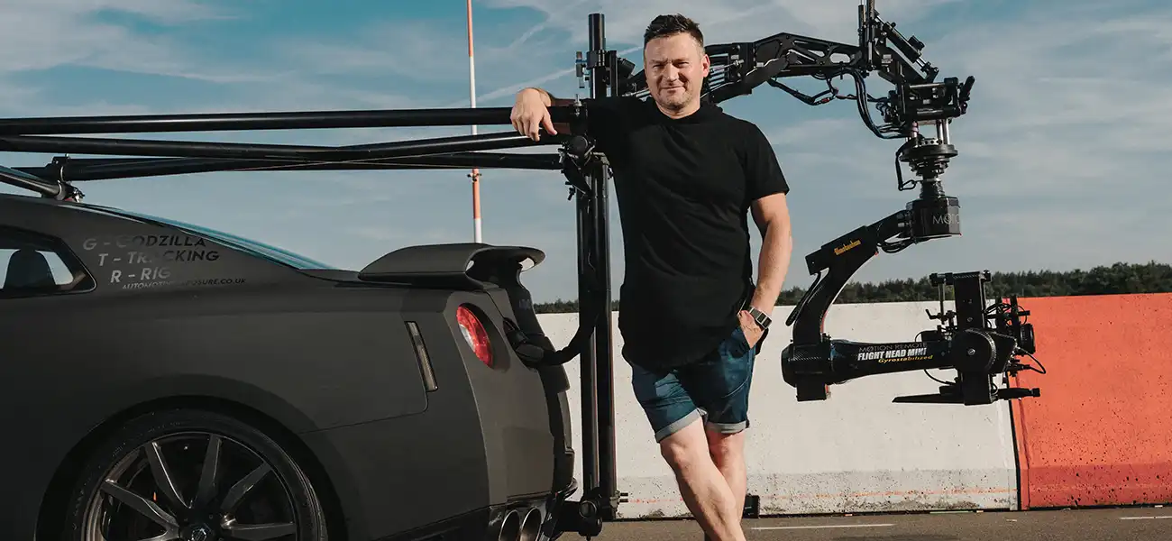 A man standing at the back of dark gray Nissan GT-R.