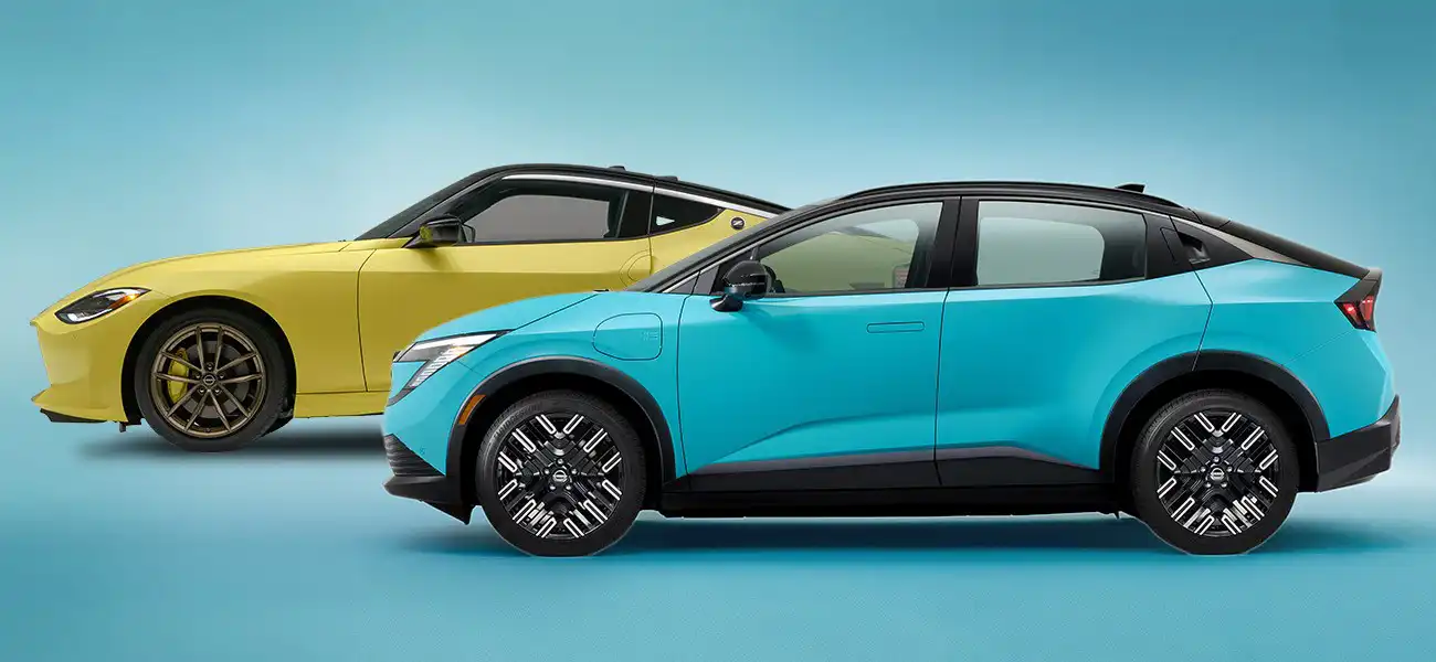 A yellow Nissan Z displayed behind a blue Nissan LEAF in front of a blue backdrop