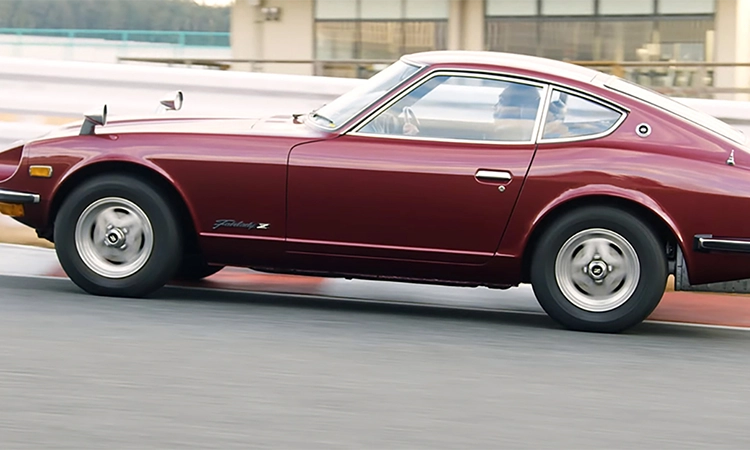 A red Nissan Z driving uphill in a city.