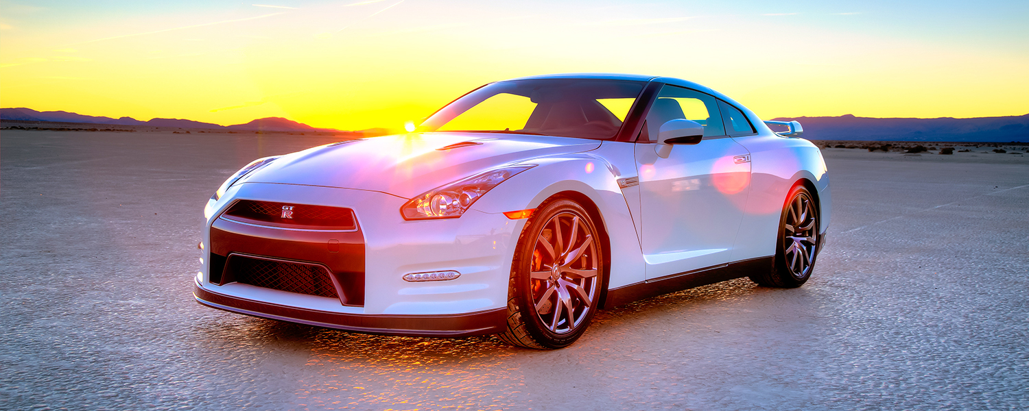 A white 2014 Nissan GT-R with sunset behind