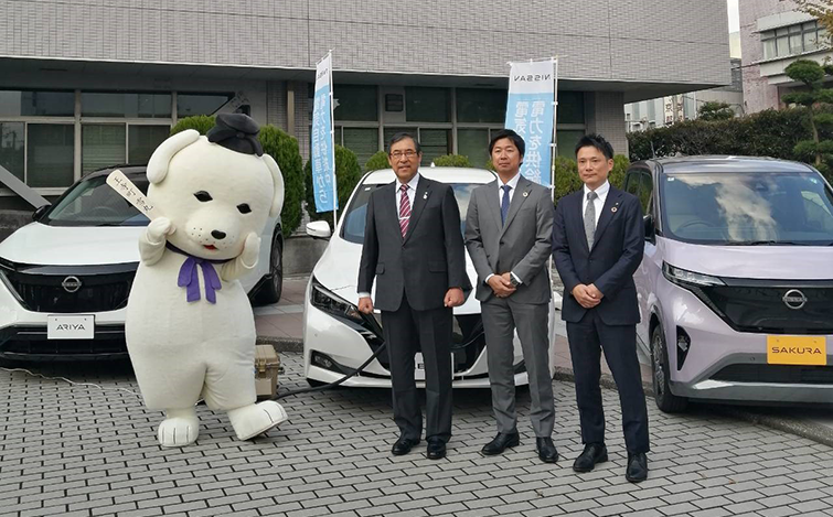 電気自動車の前で記念撮影する各代表者