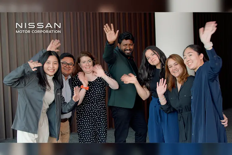 Seven people facing forward and smiling and waving