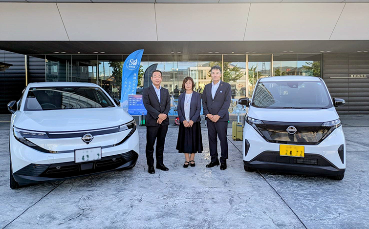 電気自動車の前で記念撮影をする各団体代表者