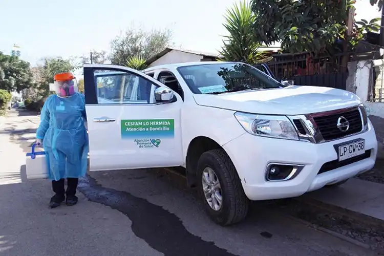 Una persona con equipo de protección parada junto a un vehículo blanco.