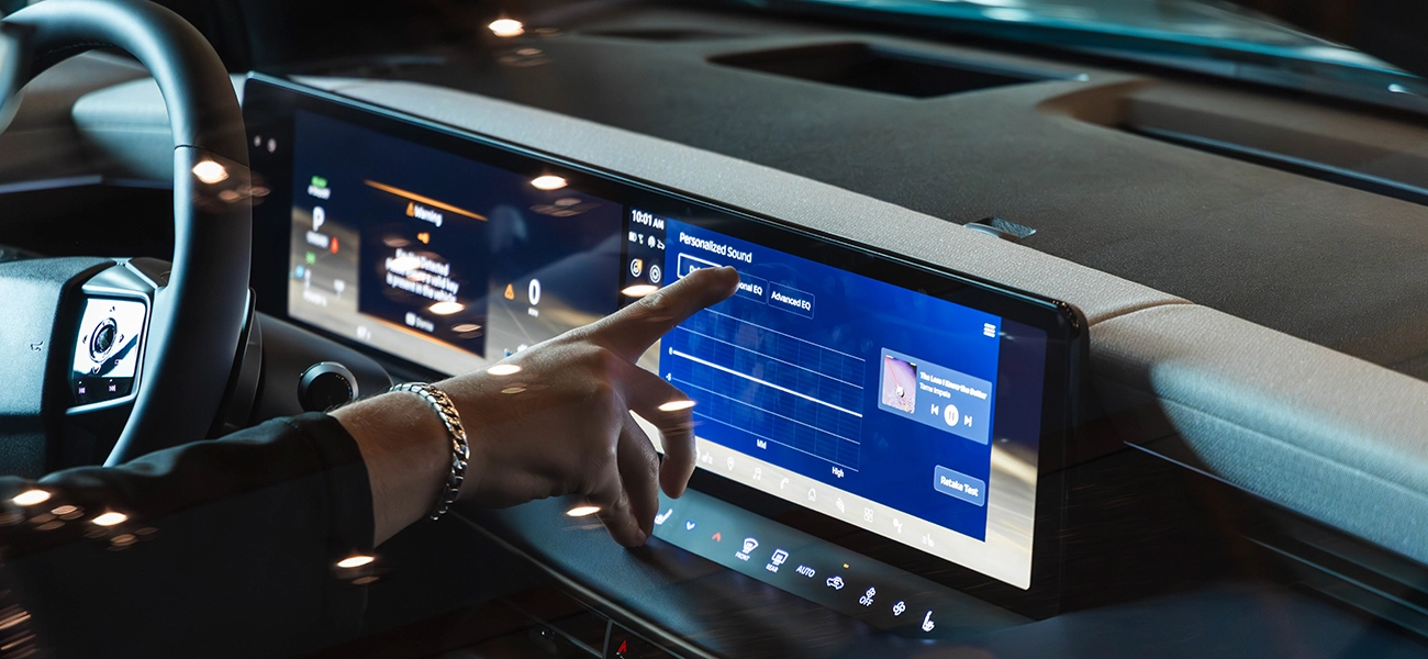 Angled view of a finger hovering over an infotainment screen to press touch screen call to actions.