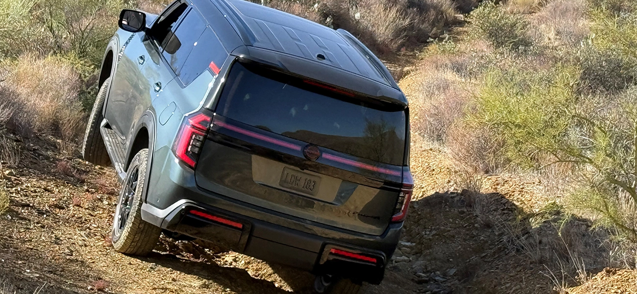 The 2025 Nissan Armada PRO-4X scaling a rocking hill covered in brush.