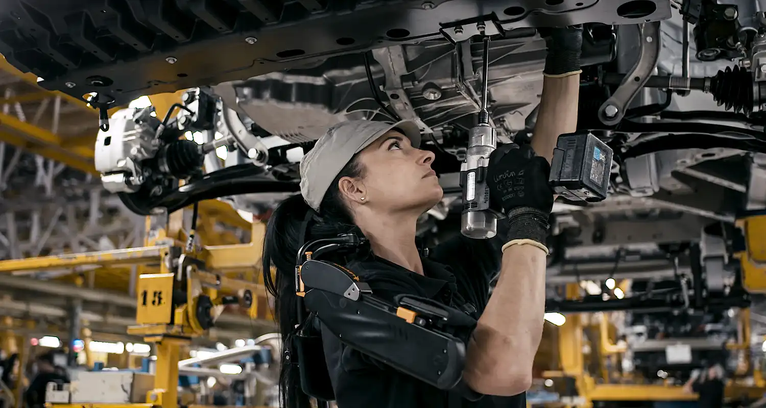 Una persona que trabaja en un automóvil asistida por un equipo.
