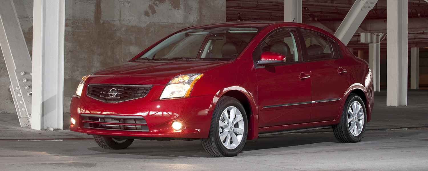 A picture of a red Nissan Sentra parked in an underground parking lot.