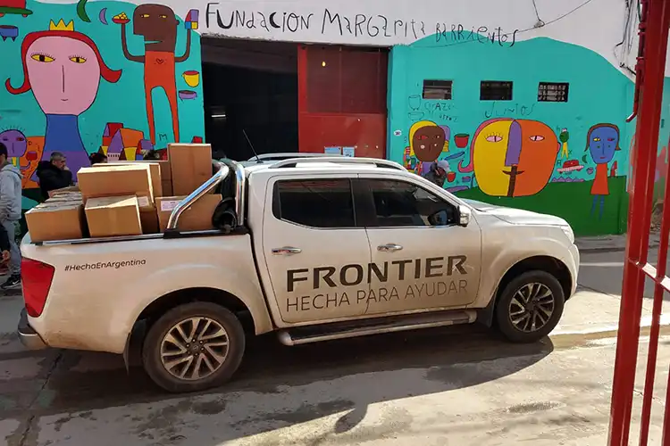 Un Frontier blanco estacionado frente a un edificio con pinturas coloridas.