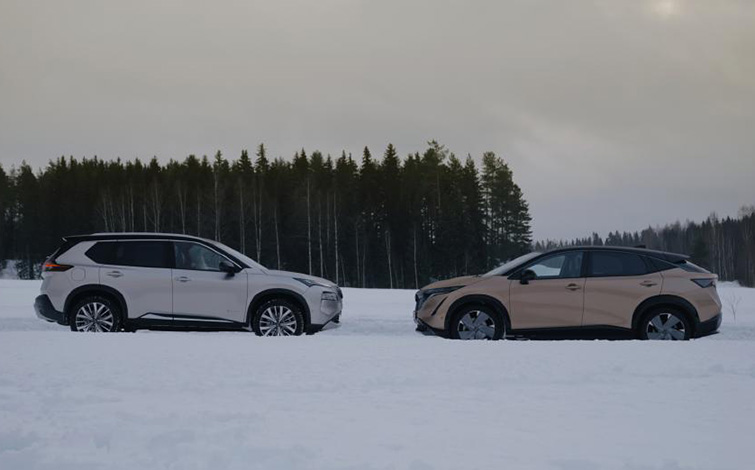 The X-Trail e-POWER e-4ORCE and Ariya e-4ORCE parked on the snow and facing each other with a forest in the background